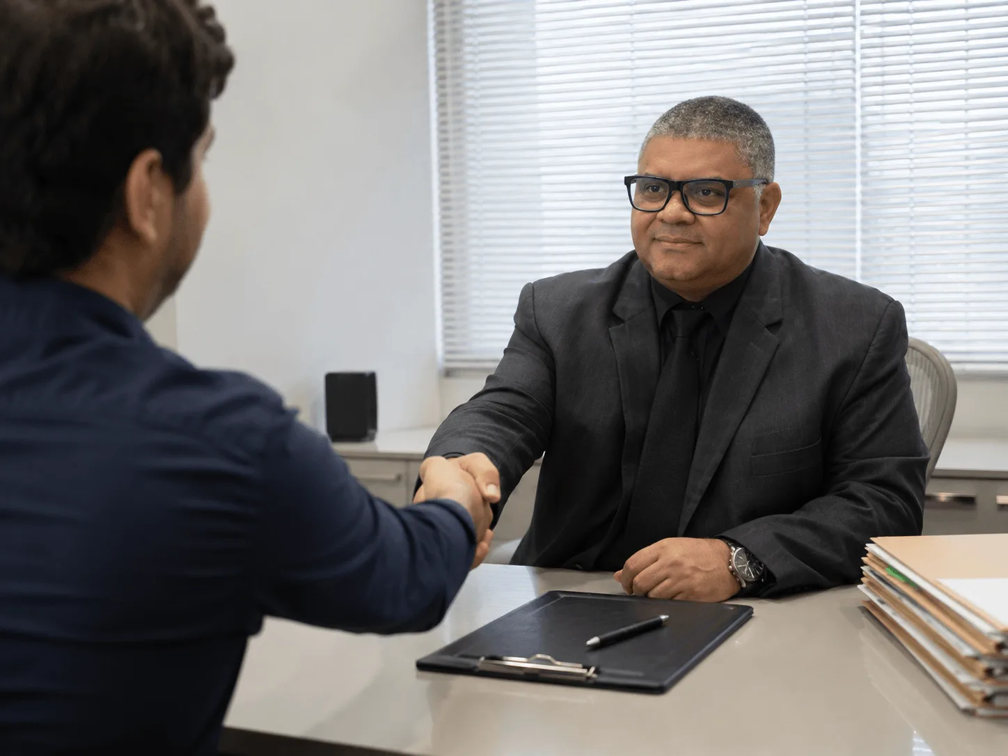 O advogado Dr. Marcelo apertando a mão de um cliente com confiança, selando a parceria e proteção na rescisão indireta.